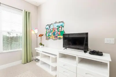a living room with a tv on a white desk at Cozy Beautiful 5 Suites close to Disney World in Orlando