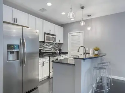 a kitchen with a stainless steel refrigerator and white cabinets at Lovely 2Bdrm 2Bath Thorton Park Condo with secure parking in Orlando