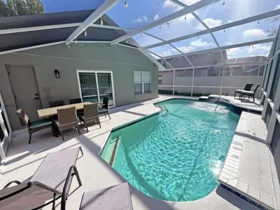 a swimming pool on a patio with a table and chairs at Stardust Villa home in Kissimmee