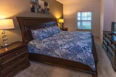 a bedroom with a bed and a dresser and lamp at Elegant, Spacious 3bedroom Near Attractions Hot Tub Pool & Gym in Kissimmee