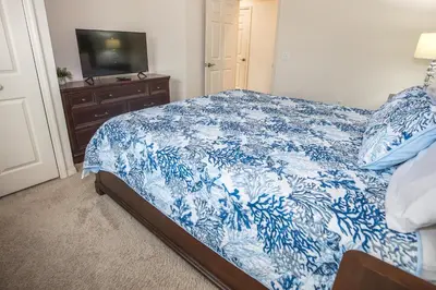a blue and white bed in a bedroom with a television at Elegant, Spacious 3bedroom Near Attractions Hot Tub Pool & Gym in Kissimmee