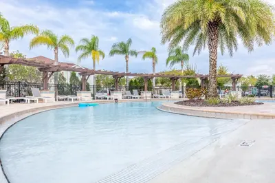 a large swimming pool with palm trees and chairs at Elegant, Spacious 3bedroom Near Attractions Hot Tub Pool & Gym in Kissimmee
