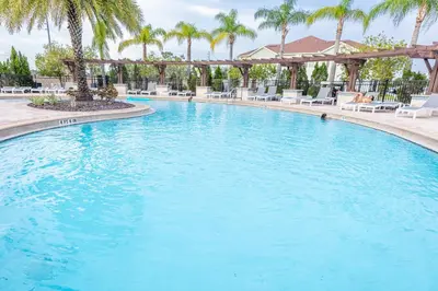 a large swimming pool with chairs and palm trees at Elegant, Spacious 3bedroom Near Attractions Hot Tub Pool & Gym in Kissimmee