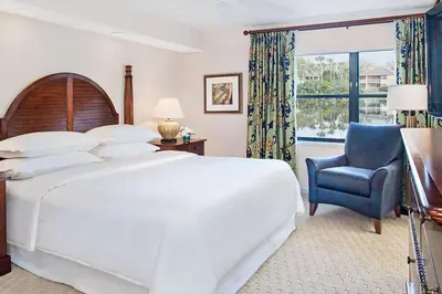 a bedroom with a large white bed and a blue chair at Have fun in this 2BD condo in a resort setting with close access to Orlando parks in Orlando