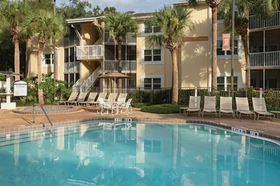 a swimming pool in front of a building with palm trees at Have fun in this 2BD condo in a resort setting with close access to Orlando parks in Orlando