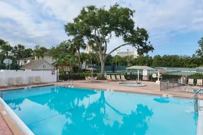 a large blue swimming pool with chairs and trees at Have fun in this 2BD condo in a resort setting with close access to Orlando parks in Orlando