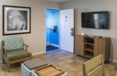 a living room with a flat screen tv and a chair at Diamond Barefootn Resort 2BD in Orlando