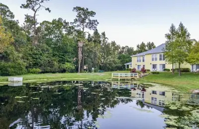 a house with a pond in front of a house at Diamond Barefootn Resort 2BD in Orlando