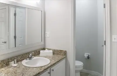 a bathroom with a sink and a toilet and a mirror at Diamond Barefootn Resort 2BD in Orlando