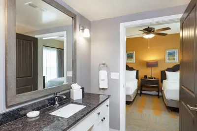 a bathroom with a sink and a mirror and a bedroom at WorldMark Kingstown Reef - 1BD Sleeps up to 4 in Orlando