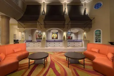 a lobby with orange couches and tables and paintings at Marriott Grande Vista 2BD villa sleeps 8 in Orlando