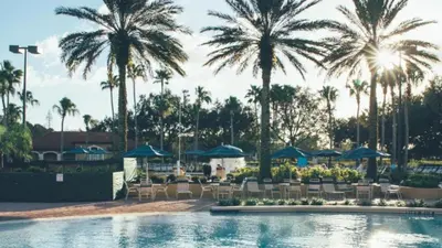 a pool with palm trees and chairs and umbrellas at Near Disney 1BD vacation condo in beautiful resort with lots of amenities in Orlando