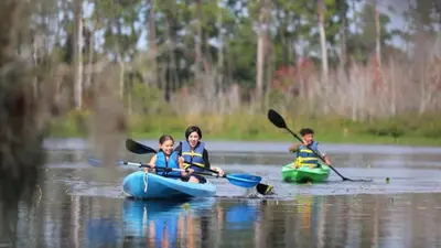 a woman and two children in kayaks on a lake at Enjoy Orlando Family Getaway in 2BD condo with lots of onsite activities in Orlando