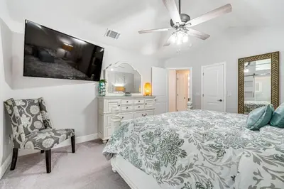 a bedroom with a bed and a tv and a chair at 5 Mi to Disney World Spacious Kissimmee Home! in Kissimmee