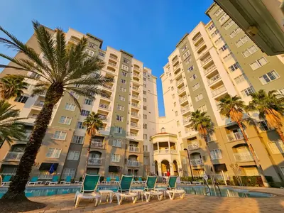 a row of chairs and a palm tree in front of a building at 1 Bedroom - Grand Suite 5 min to Universal, I-drive & Outlets in Orlando