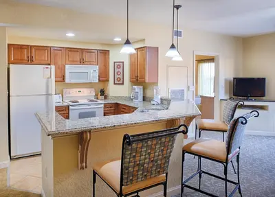 a kitchen with a white refrigerator and two chairs at Beautiful Resort in Bonnet Creek 2BD Deluxe near Walt Disney World in Orlando