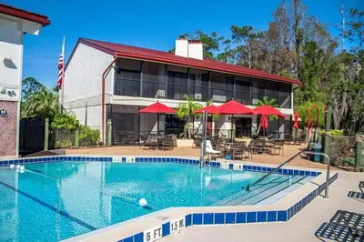 a pool in front of a hotel with red umbrellas at Diamond Bryans Spanish Cove 2BD in Orlando