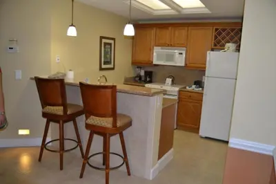 a kitchen with two bar stools and a white refrigerator at Diamond - Cypress Pointe Resort - 2BD in Orlando