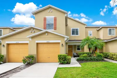 a house with two garage doors in a yard at Stylish Villa Near Disney & Universal in Kissimmee