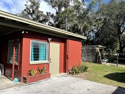 a red house with a yellow door in a yard at Downtown Groovy Studio in Orlando