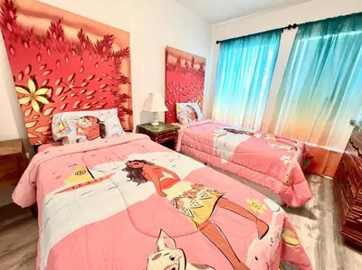 a bedroom with two beds with pink sheets with a woman on them at Sunkey Disney Home Resort 10 min from the Parks in Kissimmee