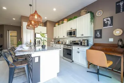 a kitchen with white cabinets and a island with chairs at Welcome to The Lion Nest. A Savanna-Inspired Oasis in Orlando
