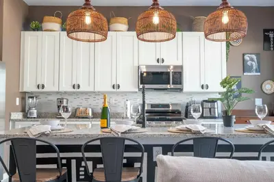 a kitchen with white cabinets and a table with chairs at Welcome to The Lion Nest. A Savanna-Inspired Oasis in Orlando