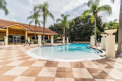 a swimming pool in front of a house with palm trees at 2 Suítes c/ Jacuzzi • 10min da Disney in Kissimmee