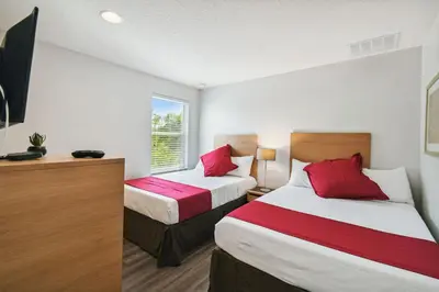 a hotel room with two beds and a window at 2 Suítes c/ Jacuzzi • 10min da Disney in Kissimmee