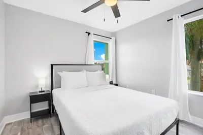 a white bedroom with a bed and a ceiling fan at Luxury Villa Near Disney I Fully Renovated in Kissimmee