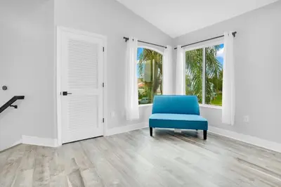 a blue chair in a white room with windows at Luxury Villa Near Disney I Fully Renovated in Kissimmee