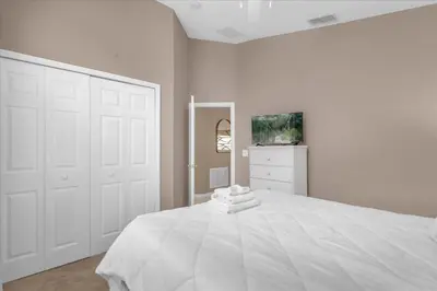 a white bedroom with a large white bed and a dresser at Summer Getaway - 5-Bedroom Home with Private Pool! in Kissimmee