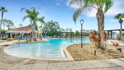 a swimming pool at a resort with palm trees at Summer Getaway - 5-Bedroom Home with Private Pool! in Kissimmee