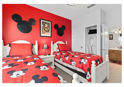 a bedroom with a red wall with mickey mouse bedding at Wheelchair-Friendly Villa Near Disney World in Orlando