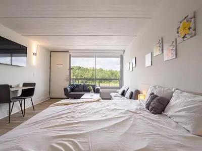 a large white bed in a room with a large window at Luxury Orlando Condo Next to Disney with lake view in Kissimmee