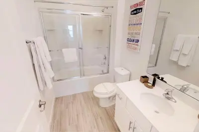a white bathroom with a toilet and a sink at 3841 Kalistoga Stylish Villa 7BD Private Pool and Game Room in Kissimmee