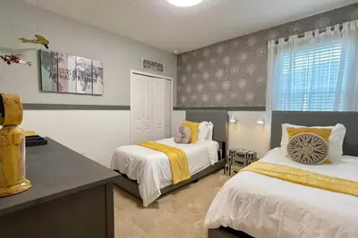 a bedroom with two beds with yellow and white sheets at 3841 Kalistoga Stylish Villa 7BD Private Pool and Game Room in Kissimmee