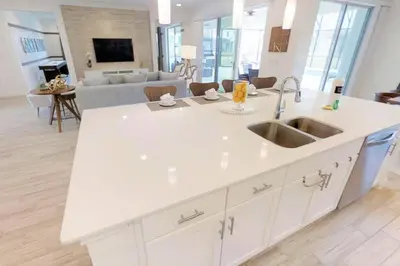 a white kitchen with a sink and a living room at 3841 Kalistoga Stylish Villa 7BD Private Pool and Game Room in Kissimmee
