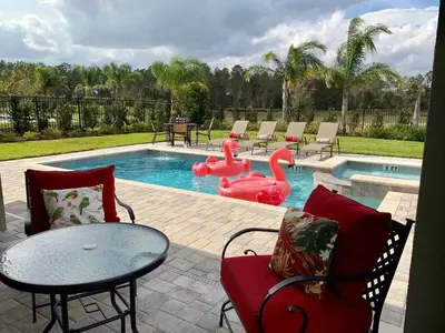 a pool with two pink flamingos and a table and chairs at 7738-IBRHAIM · 7738 Fairfax Dream Home in Orlando