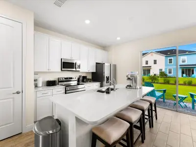 a kitchen with a large white island with bar stools at Sunshine Villa Near Disney With Margaritaville Resort & Island H20 Waterpark Access - 2922Cl in Orlando