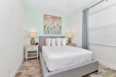 a white bedroom with a bed and two night stands at Lovely Villa Cottage Near Disney With Margaritaville Resort & Island H20 Waterpark Access - 2931Cl in Orlando