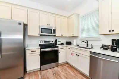 a kitchen with white cabinets and a stainless steel refrigerator at Crystal Cottage Near Disney With Margaritaville Resort & Island H2O Access - 8033Ls in Orlando