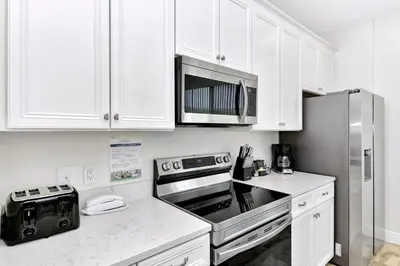 a kitchen with white cabinets and a stainless steel refrigerator at Tropical Green Villa Near Disney With Margaritaville Resort & Island H20 Access - 8142Cp in Kissimmee