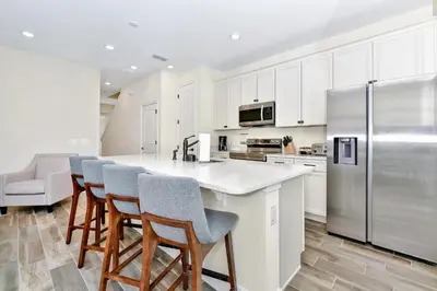 a kitchen with white cabinets and a bar with stools at Summer Breeze Villa Near Disney With Margaritaville Resort & Island H20 Waterpark Access - 2960Cs in Orlando