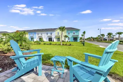 two blue chairs sitting on a patio in front of a house at Blissful Pink Villa Near Disney With Margaritaville Resort & Island H20 Access - 8103Cp in Orlando