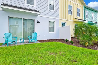 a house with two blue chairs on the front yard at Cool Cottage Near Disney With Margaritaville Resort & Island H20 Waterpark Access - 3184Cs in Orlando