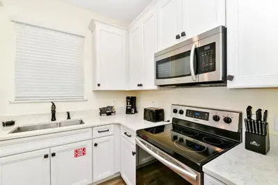 a kitchen with white cabinets and a stove and microwave at Beachy Daze Cottage Near Disney With Margaritaville Resort & Island H20 Waterpark Access - 2916Sr in Orlando