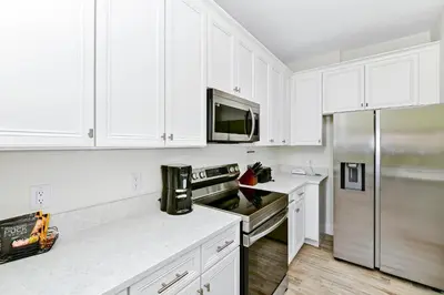 a kitchen with white cabinets and a stainless steel refrigerator at Dreamy Villa Near Disney With Margaritaville Resort & Island H2O Access - 3020Cs in Orlando