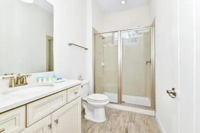 a white bathroom with a toilet and a shower at Sunny Cottage Near Disney With Margaritaville Resort & Island H20 Waterpark Access - 3013Sp in Orlando