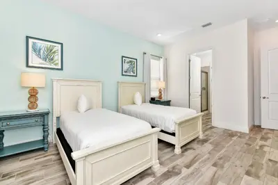 two beds in a room with blue walls and wooden floors at This Pink Cottage Near Disney With Margaritaville Resort & Island H20 Access - 8141Su in Orlando